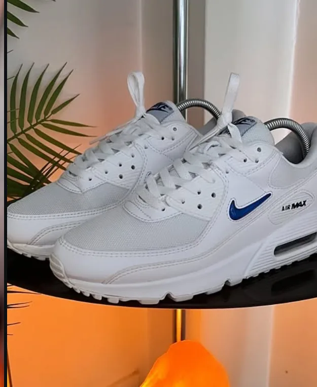 White Nike Air Max 90s with a blue jewel swoosh on the shelf