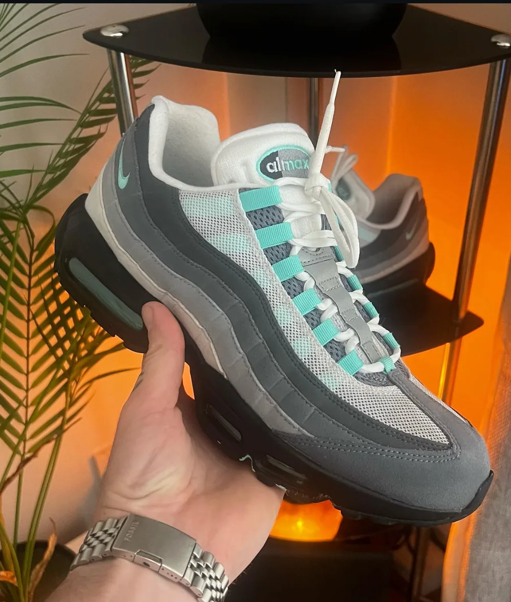 Nike Air Max 95 in grey and teal after cleaning, held up in front of the lamp-lit shelf
