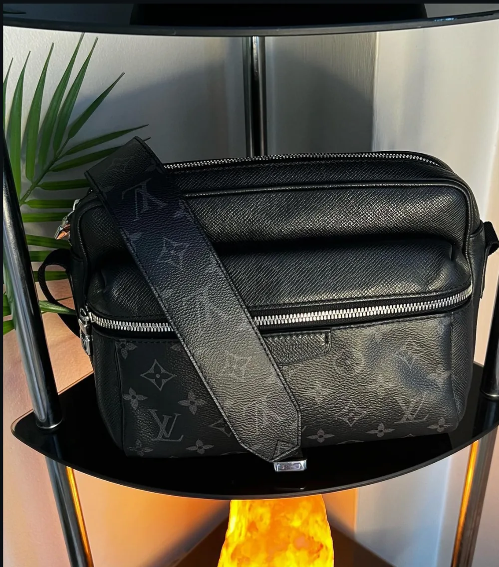 Black Louis Vuitton messenger bag sitting on the glass shelf after cleaning